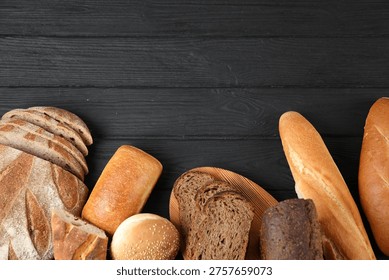 Different types of bread loaves on black wooden table, flat lay. Space for text