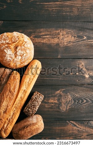 Different types of bread loaves on wooden background with copy space. Bakery, delicious food concept. Top view