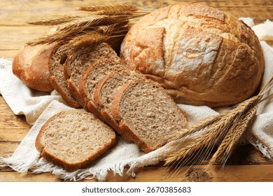 Different types of bread and wheat spikes on wooden table, closeup