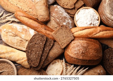 Different types of bread and wheat spikes on wooden table, flat lay