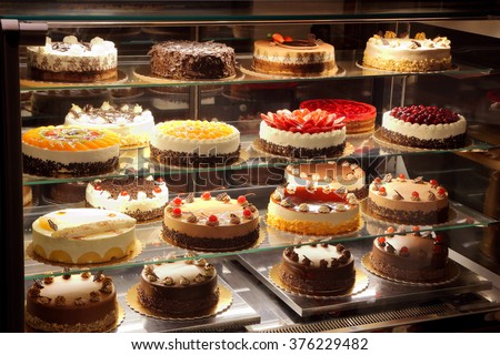 Different types of cakes in pastry shop glass display 


