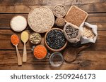 Different types of cereals, seeds and legumes on wooden table, flat lay