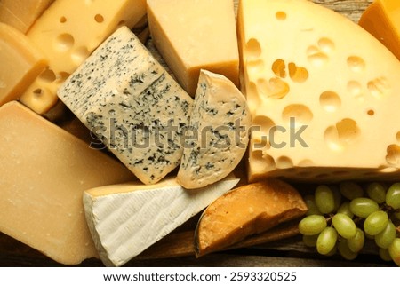 Different types of cheese and grapes on wooden table, flat lay