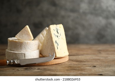 Different types of cheese and knife on wooden table. Space for text