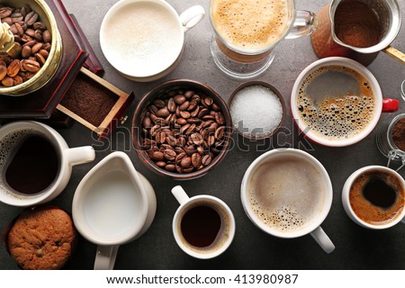 Different types of coffee in cups on dark table, top view