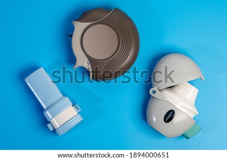 Different types of COPD or Asthma medication instruments ,discus and handihaler and a capsule inhaler.On blue background.