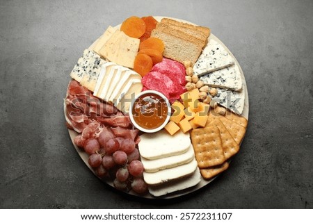 Different types of cut cheese and other snacks on grey textured table, top view