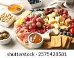 Different types of delicious cheese and other snacks on light grey table, closeup