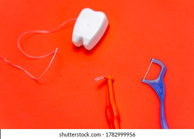 Different Types Of Dental Floss And Tooth Picks On Red Background. Dental Floss In Tooth Toy Shape.