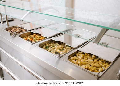 Different types of dishes in containers on the buffet table in the hotel restaurant