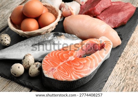 Different types of fresh raw meat, fish and eggs on wooden table, closeup