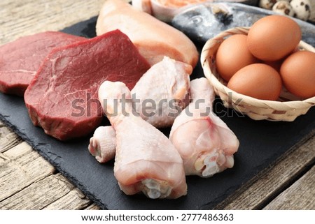 Different types of fresh raw meat, fish and eggs on wooden table, closeup