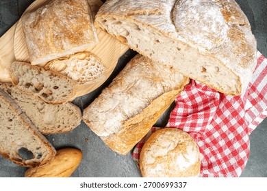 Different types of freshly baked bread displayed on a dark surface and wooden board