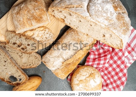 Different types of freshly baked bread displayed on a dark surface and wooden board
