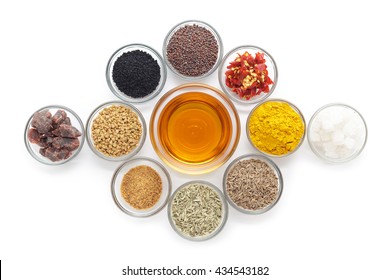 Different types of Indian spices with mustard oil in glass bowl isolated on white background. Top view.