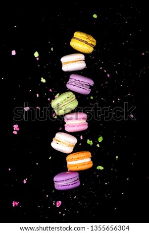 Different types of macaroons in motion falling on black background background. Sweet and colorful french macaroons falling or flying in motion