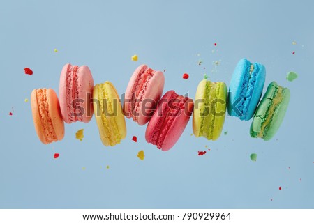 Different types of macaroons in motion falling on blue background. Sweet and colourful french macaroons falling or flying in motion. 