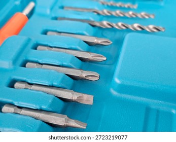 Different types of metal drill bits and screwdriver bits arranged in a blue tool organizer tray used for various tasks