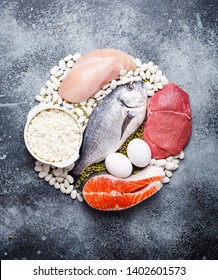 Different Types Of Natural Healthy Foods Contain Protein: Fish, Meat, Chicken, Eggs, Dairy Products, Beans On Gray Concrete Background, Top View, Closeup. Protein Foods For Diet And Proper Nutrition 
