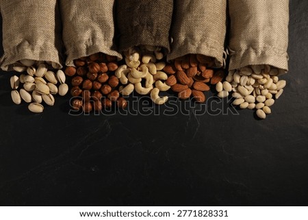 Different types of nuts on black table, flat lay. Space for text