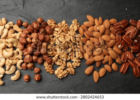 Different types of nuts on dark textured table, flat lay. Vegan protein snack