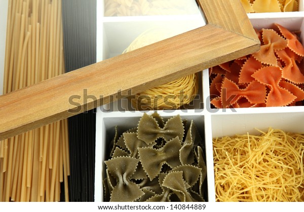 Different types of pasta in white wooden box\
sections close-up