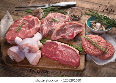 Different types of raw meat - beef, pork, lamb, chicken on a wooden board. - Shutterstock ID 1205291680