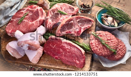Different types of raw meat - beef, pork, lamb, chicken on a wooden board.