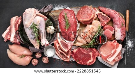 Different types of raw meat - beef, pork, lamb, chicken on dark background. Top view, copy space