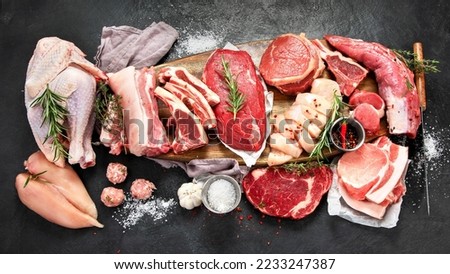Different types of raw meat - beef, pork, lamb, chicken on dark background. Top view