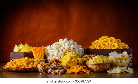 Different types of snacks, chips, nuts and popcorn in still life