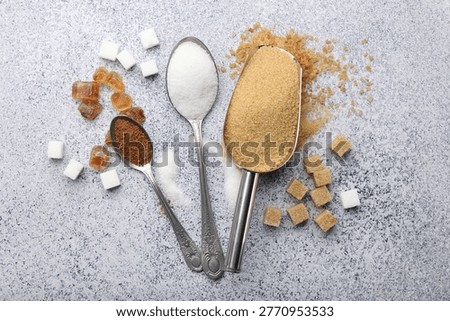 Different types of sugar, scoop and spoons on light grey table, flat lay