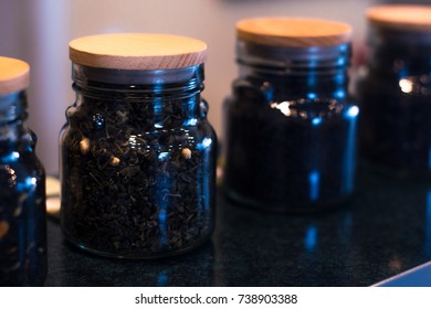 Different types of tea in glass jars on a blurred background