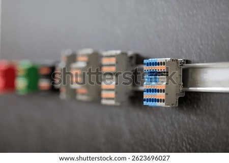 Different types of terminal blocks mounted on DIN rail close up. Selective focus.