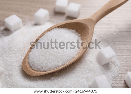 Different types of white sugar and spoon on table, closeup