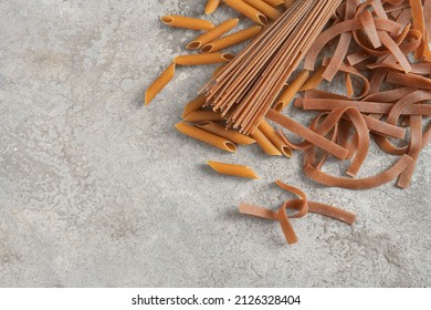 Different Types Of Wholegrain Pasta, Tagliatelle, And Penne Rigate, On A Rustic Gray Stone Background, Healthy Noodle Alternative, Copy Space, Flat Lay From Above