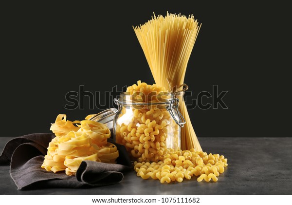 Different\
uncooked pasta on table against dark\
background