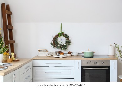 Different Utensils On Kitchen Counter And Easter Decor Near White Wall