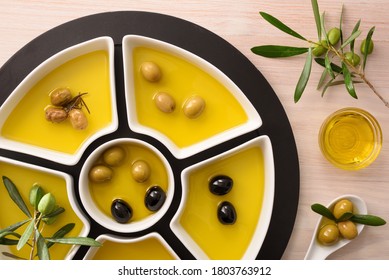 Different Variants Of Olives To Eat And Oil In Containers On Wooden Kitchen Bench. Top View.