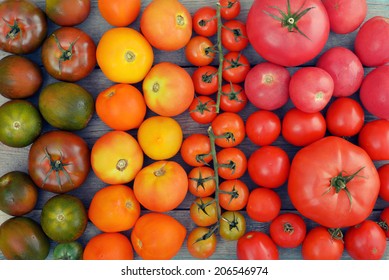 Different varieties of tomatoes on wooden background. Top view.