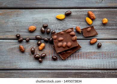 Different variety of chocolate and hazelnut on wooden background top view