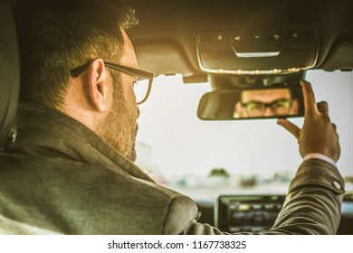 Different view of the world. Young man sitting in car and adjusts the mirror. Close up.