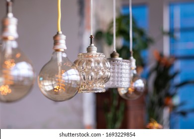 Different vintage glass lamps hanging in a city loft interior in Strijp S, Eindhoven, The Netherlands. A mix and mach, eclectic styled home with bohemian influences creating a warm cosy feeling