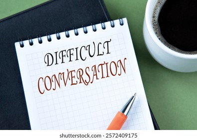 DIFFICULT CONVERSATION - words in notebook on green background with cup of coffee. Info concept