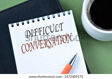 DIFFICULT CONVERSATION - words in notebook on green background with cup of coffee. Info concept