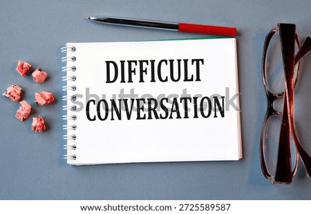 DIFFICULT CONVERSATION - words in notebook on gray background with glasses and pen