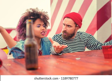 Difficult Conversation. Young Tired Couple Sitting At The Table After Big Party And Having Expressive Conversation