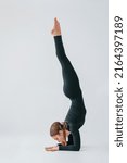 Difficult exercises. Young woman in sportive clothes doing gymnastics indoors.