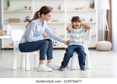 Difficult kid concept. Emotional angry little boy screaming and covering ears during consultation at psychologist, worried therapist trying to calm down patient at office - Powered by Shutterstock