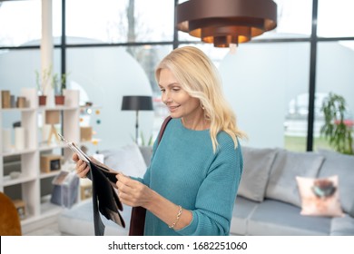 Difficulties Of Choice. Woman With Fabric Samples In Hands Standing In Studio Of Furniture Store, Thinking Decision Maker.